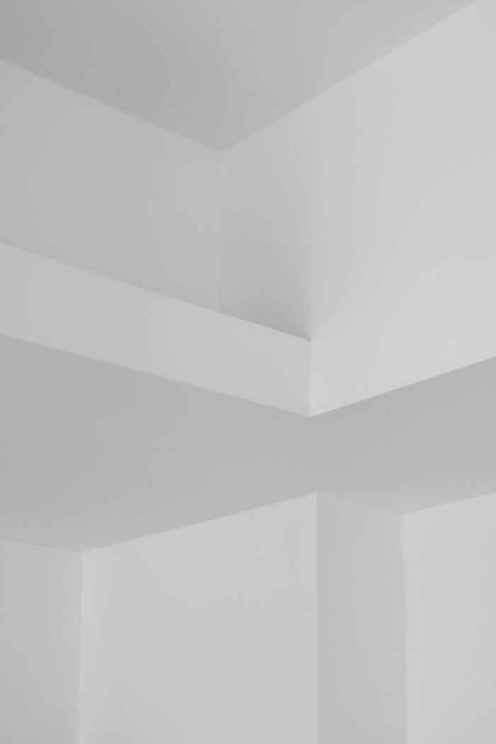 About A minimalist room showcasing a geometric white ceiling. Ideal for modern design concepts.